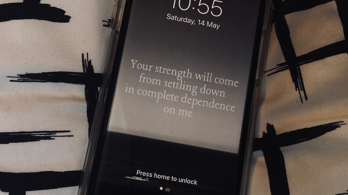 A photo of Maja's phone background with the phrase "your strength will come from settling down in complete dependence in me" on a moody sea and sky landscape